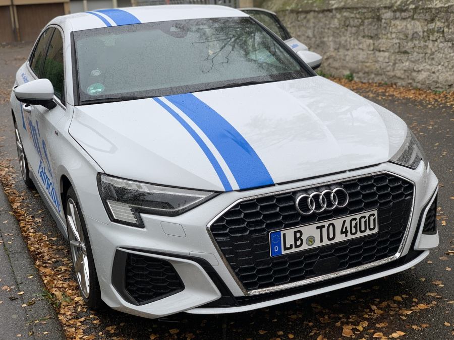 Weißer Audi A3 mit blauem Streifen und Fahrschul-Beschriftung