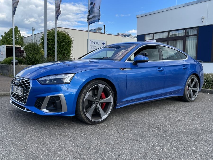 Blauer Audi S5 Sportback vor dem Fahrschulgebäude