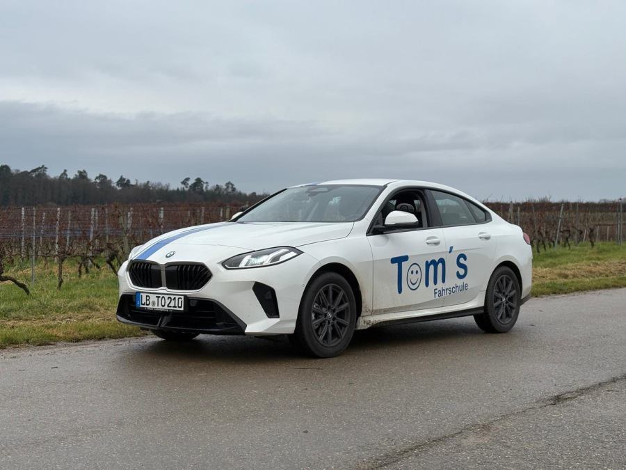 Der BMW 220 Grand Coupé von Tom's Fahrschule auf einer Straße zwischen Weinbergen